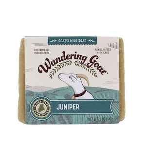 May include: A bar of goat's milk soap with a label that says "Wandering Goat" and "Juniper". The label also says "Sustainable Ingredients" and "Handcrafted with Care". The soap is 5 ounces (140 grams).