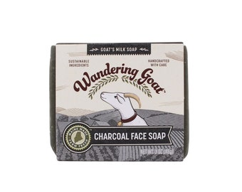 May include: A bar of charcoal face soap with a green label featuring a cartoon goat and the text "Wandering Goat" and "Goat's Milk Soap". The label also says "Sustainable Ingredients" and "Handcrafted with Care". The soap is made in Maine and weighs 85 grams.