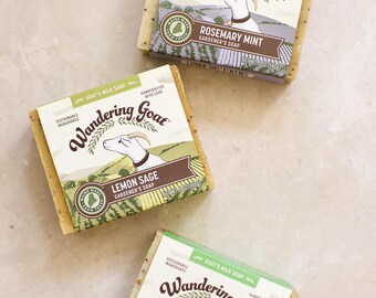 May include: Three rectangular bars of Wandering Goat goat's milk soap, each featuring a label with a goat illustration and the text Rosemary Mint, Lemon Sage, and Basil Lime. Each bar weighs 5 oz and includes sustainable ingredients.