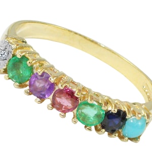 Puede incluir: Un anillo de banda de oro con siete piedras preciosas engastadas en fila. Las piedras preciosas son de color verde esmeralda, morado amatista, rosa, verde esmeralda, azul zafiro y turquesa.