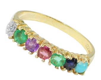 Op de afbeelding: Een gouden ring met zeven edelstenen in een rij gezet. De edelstenen zijn smaragdgroen, amethistpaars, roze, smaragdgroen, saffierblauw en turquoise.