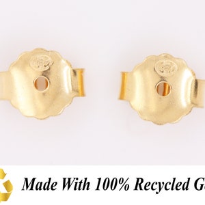 May include: Two gold-colored earring backs. The backs are made of metal and have a rounded shape with a small hole in the center. The backs are designed to secure earrings to the earlobe.  Made with 100% Recycled Gold.