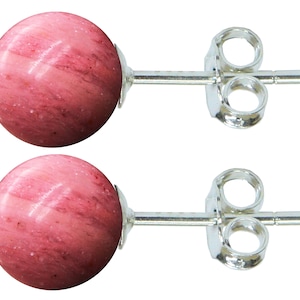 May include: A pair of round, pink gemstone stud earrings. The earrings have a polished, marbled appearance with silver posts and backings. The gemstones are a soft pink color with darker pink veining.