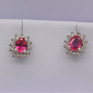 Peut inclure: Une paire de boucles d'oreilles en argent avec des pierres ovales roses entourées de petites pierres blanches.