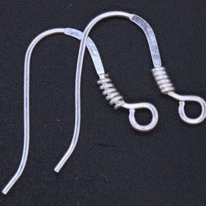 Peut inclure: Deux crochets d'oreille en argent avec un détail de fil enroulé. Les crochets sont en métal et ont une finition brillante.
