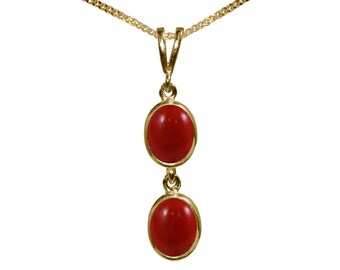 Può includere: Una collana con catena d'oro con un ciondolo con due pietre ovali rosse.