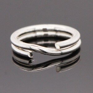 May include: A silver ring with a twisted design. The ring is made of two pieces of metal that are intertwined.
