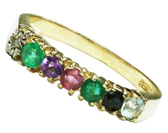 Op de afbeelding: Een gouden ring met zeven edelstenen. De edelstenen zijn smaragdgroen, amethistpaars, roze, smaragdgroen, zwart en lichtblauw.