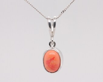 Può includere: Una collana con un ciondolo in argento e una pietra ovale di corallo. Il ciondolo è su una catena d'argento.