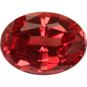 May include: A deep red oval gemstone with a faceted cut. The gemstone is set against a white background.