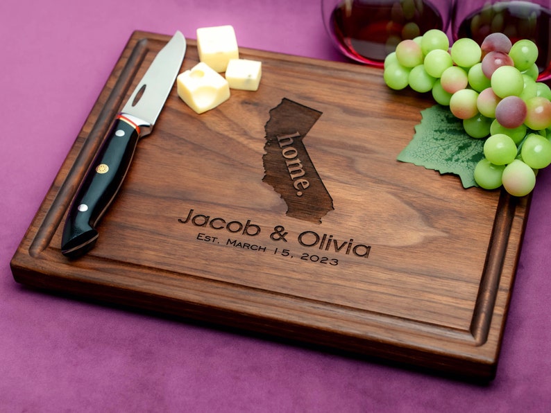 Handmade from natural hardwood personalized cutting board. Never stained, 100% food safe, only finished with food grade mineral oil and beeswax. 12x9 inches Walnut Wooden board with central design number 602 with US state, first names, and date.