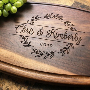 Handmade from natural hardwood personalized cutting board. Never stained, 100% food safe, only finished with food grade mineral oil and beeswax. 12x9 inches Walnut Arched Wooden board with central design number 215 with first names and year.