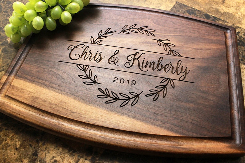 Handmade from natural hardwood personalized cutting board. Never stained, 100% food safe, only finished with food grade mineral oil and beeswax. 12x9 inches Walnut Arched Wooden board with central design number 215 with first names and year.