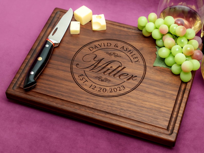 Handmade from natural hardwood personalized cutting board. Never stained, 100% food safe, only finished with food grade mineral oil and beeswax. 12x9 inches Walnut Wooden board with central design number 001 with first names, last name, and date.