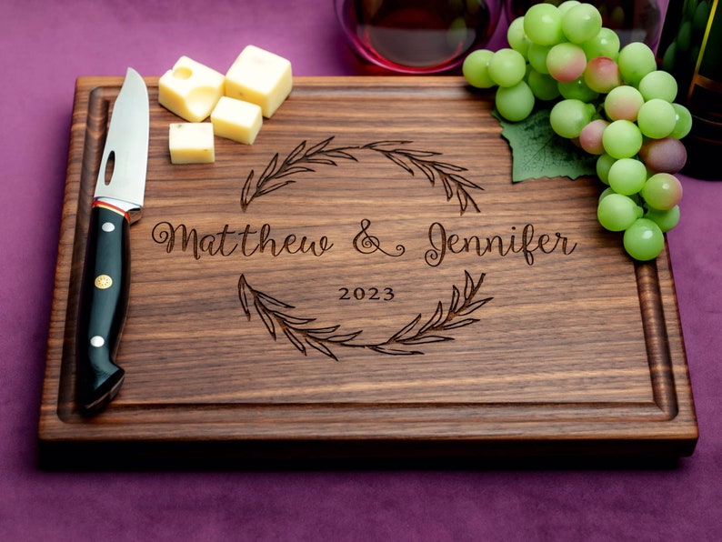 Handmade from natural hardwood personalized cutting board. Never stained, 100% food safe, only finished with food grade mineral oil and beeswax. 12x9 inches Walnut Wooden board with central wreath design number 413 with first names and date.