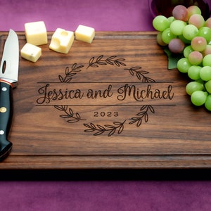 Handmade from natural hardwood personalized cutting board. Never stained, 100% food safe, only finished with food grade mineral oil and beeswax. 12x9 inches Walnut Wooden board with central design number 215 with first names and year.