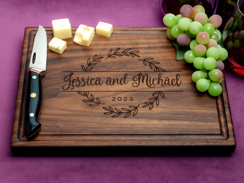 Handmade from natural hardwood personalized cutting board. Never stained, 100% food safe, only finished with food grade mineral oil and beeswax. 12x9 inches Walnut Wooden board with central design number 215 with first names and year.