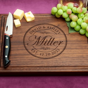 Handmade from natural hardwood personalized cutting board. Never stained, 100% food safe, only finished with food grade mineral oil and beeswax. 12x9 inches Walnut Wooden board with central design number 001 with first names, last name, and date.