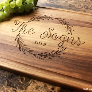 Handmade from natural hardwood personalized cutting board. Never stained, 100% food safe, only finished with food grade mineral oil and beeswax. 12x9 inches Walnut Wooden board with central wreath design number 413 with first names and date.