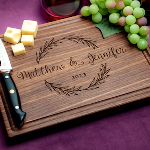 Handmade from natural hardwood personalized cutting board. Never stained, 100% food safe, only finished with food grade mineral oil and beeswax. 12x9 inches Walnut Wooden board with central wreath design number 413 with first names and date.