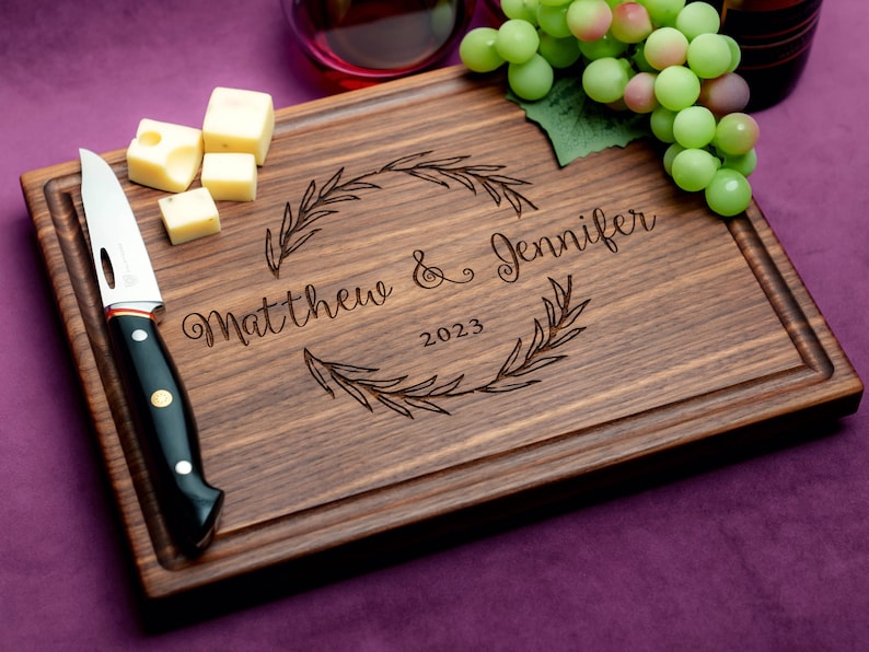 Handmade from natural hardwood personalized cutting board. Never stained, 100% food safe, only finished with food grade mineral oil and beeswax. 12x9 inches Walnut Wooden board with central wreath design number 413 with first names and date.