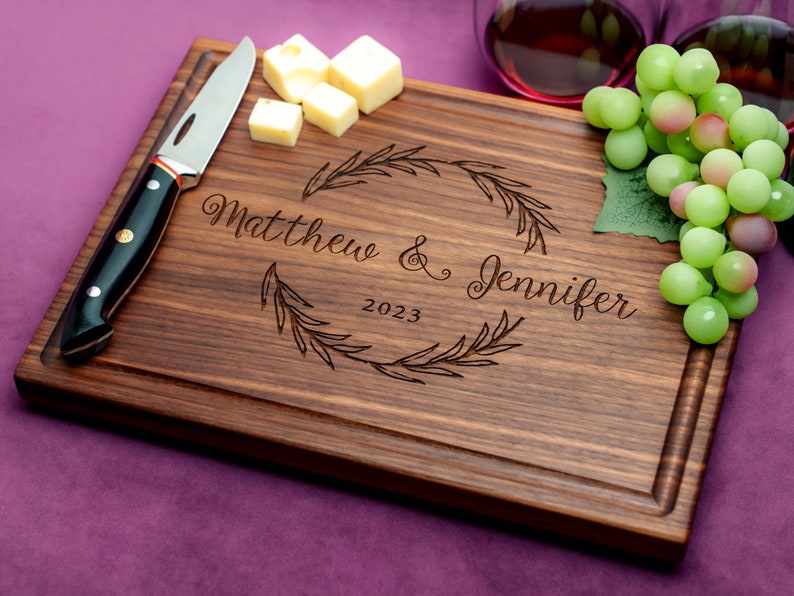 Handmade from natural hardwood personalized cutting board. Never stained, 100% food safe, only finished with food grade mineral oil and beeswax. 12x9 inches Walnut Wooden board with central wreath design number 413 with first names and date.