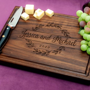 Handmade from natural hardwood personalized cutting board. Never stained, 100% food safe, only finished with food grade mineral oil and beeswax. 12x9 inches Walnut Wooden board with central design number 215 with first names and year.