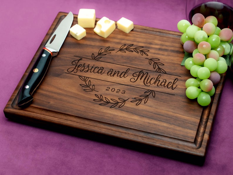 Handmade from natural hardwood personalized cutting board. Never stained, 100% food safe, only finished with food grade mineral oil and beeswax. 12x9 inches Walnut Wooden board with central design number 215 with first names and year.