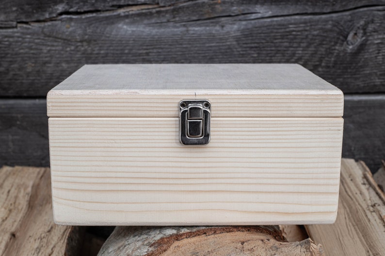 May include: A plain wooden box with a hinged lid and a silver latch. The box is made of light wood and has a natural finish.