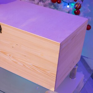 Pu&ograve; includere: Una scatola di legno chiaro con una chiusura in ottone. La scatola &egrave; appoggiata su una superficie di vetro.