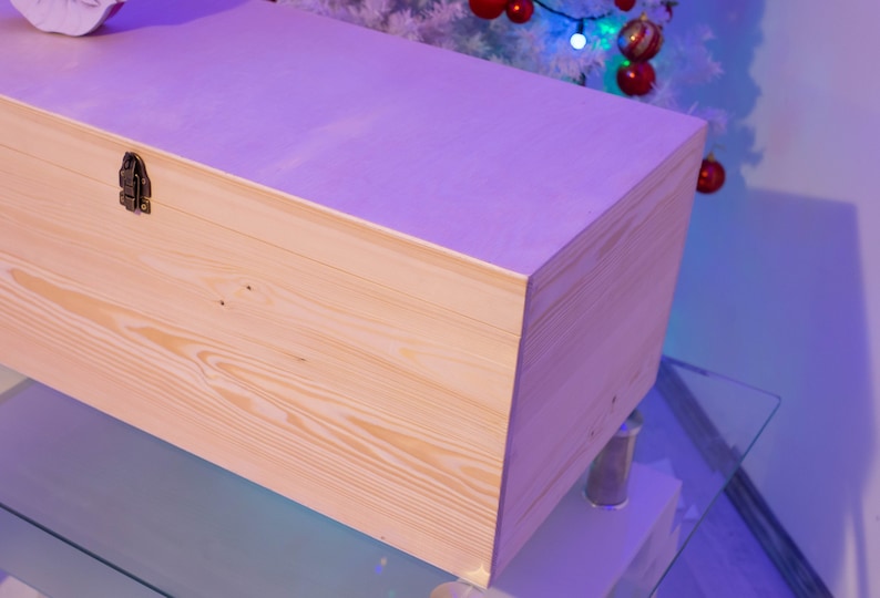 Pu&ograve; includere: Una scatola di legno chiaro con una chiusura in ottone. La scatola &egrave; appoggiata su una superficie di vetro.