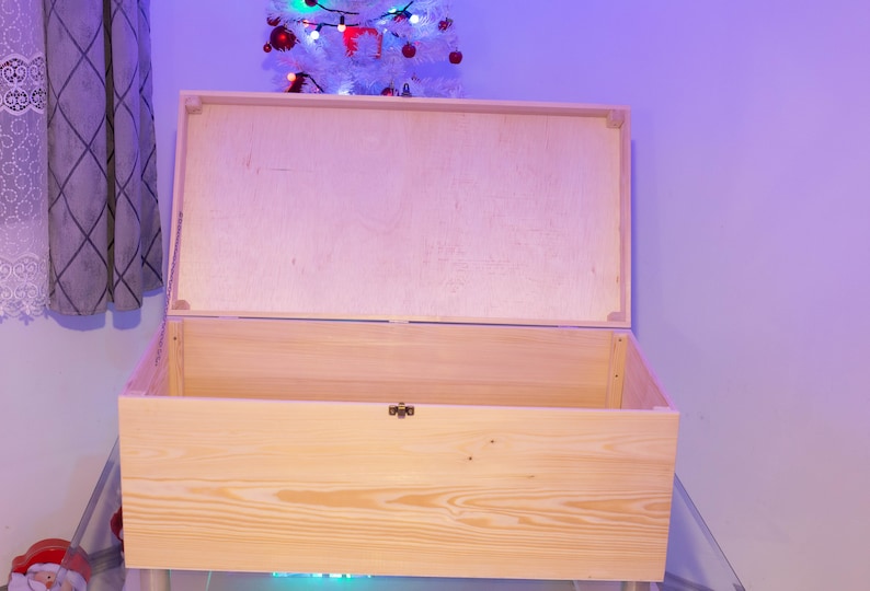 Pu&ograve; includere: Una scatola di legno naturale con un coperchio incernierato. Il coperchio &egrave; aperto e la scatola &egrave; vuota.