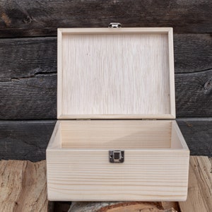 May include: An empty wooden box with a hinged lid and a metal clasp. The box is made of light-coloured wood and has a natural finish.