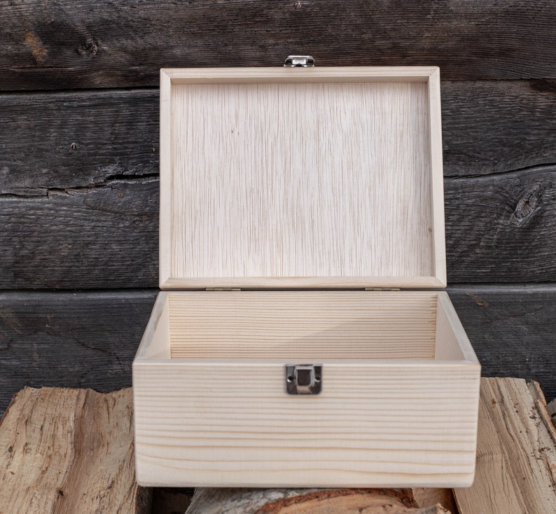 May include: An empty wooden box with a hinged lid and a metal clasp. The box is made of light-coloured wood and has a natural finish.