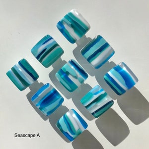 May include: Ten square glass tiles with a seascape design. The tiles are blue, white and green with a striped pattern. The tiles are arranged in a grid pattern. The text "Seascape A" is in the bottom left corner of the image.