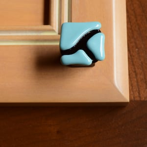Könnte beinhalten: Ein blauer und schwarzer geometrischer Schrank-Knopf mit modernem Design.