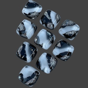 May include: Nine square glass tiles with a black and white marbled pattern. The tiles have a silver metallic fleck throughout.