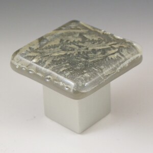 May include: Square glass cabinet knob with a gray and white marbled design. The knob is mounted on a square base.