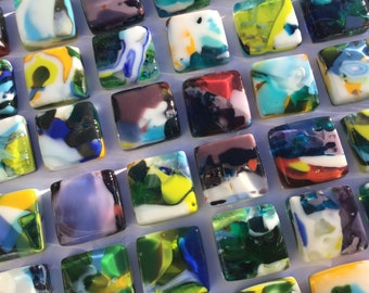 May include: A collection of colorful, square glass tiles with abstract patterns. Each tile features a unique combination of colors, including blue, green, red, yellow, and white.
