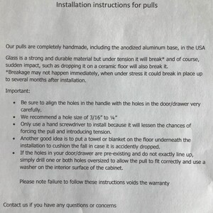 May include: Installation instructions for handmade cabinet pulls. The instructions include information about aligning holes, recommended drill bit size, and how to prevent damage during installation. The text also states that failure to follow these instructions voids the warranty. Contact information is provided at the bottom of the page.