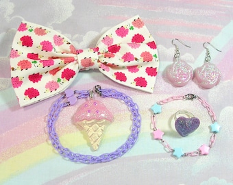 May include: A collection of whimsical accessories, including a bow tie with a hedgehog print, earrings, bracelets, and a ring. The jewelry features pastel colors, glitter, and star and heart accents. The ice cream cone pendant is a standout.