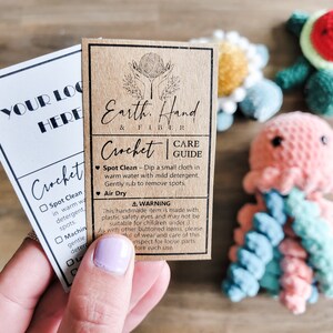 May include: A brown card with the text "Earth, Hand & Fiber" and "Crochet Care Guide" with instructions for spot cleaning and air drying. The card is next to a white card with the text "Your Logo Here" and a checklist for crochet care instructions.