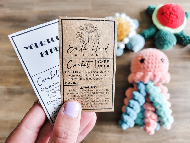 May include: A brown card with the text "Earth, Hand & Fiber" and "Crochet Care Guide" with instructions for spot cleaning and air drying. The card is next to a white card with the text "Your Logo Here" and a checklist for crochet care instructions.