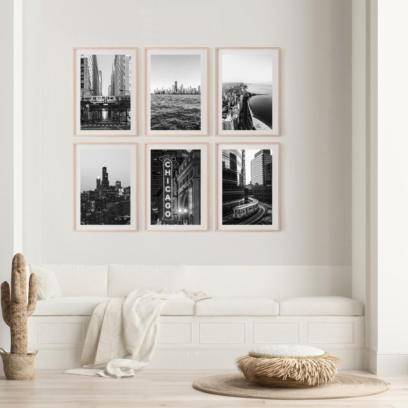May include: A set of six black and white photographs of Chicago cityscapes. The photos are framed in a light wood frame and are arranged in a grid pattern on a white wall. The photos show different views of the city, including the skyline, the river, and the streets.