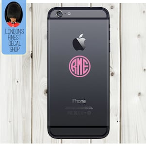 Könnte beinhalten: Ein schwarzes iPhone mit einem rosa Monogramm-Aufkleber mit den Buchstaben RME in einem Kreis. Das Apple-Logo und das Wort "iPhone" sind auf der Rückseite des Telefons aufgedruckt. Das Bild enthält auch ein Logo mit der Aufschrift "LONDON'S FINEST DECAL SHOP".
