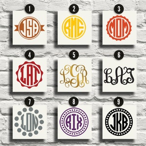 Può includere: Nove diversi design di monogrammi su schede quadrate. I monogrammi presentano varie iniziali in diversi caratteri e colori, tra cui marrone, giallo, rosso, oro, nero, grigio e viola. I disegni sono visualizzati su un muro di mattoni bianchi.