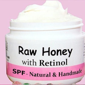 May include: A white jar with a pink label that reads "Raw Honey with Retinol SPF - Natural & Handmade".