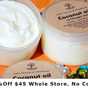 May include: Two white plastic jars of coconut oil with brown labels that say "100% Natural & Handmade Coconut Oil with Vinegar (acv) Dry Skin - Face Moisturizer" and list the ingredients. The jars are on a bright orange surface with white and green marbles.