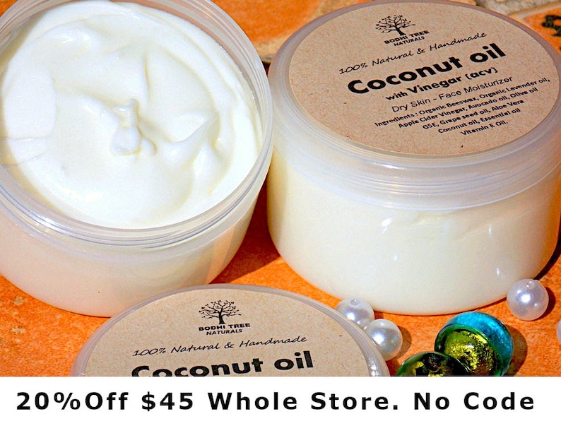 May include: Two white plastic jars of coconut oil with brown labels that say "100% Natural & Handmade Coconut Oil with Vinegar (acv) Dry Skin - Face Moisturizer" and list the ingredients. The jars are on a bright orange surface with white and green marbles.