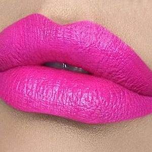 May include: Close-up of a pair of lips wearing bright pink lipstick. The lipstick has a glossy finish and is applied evenly.